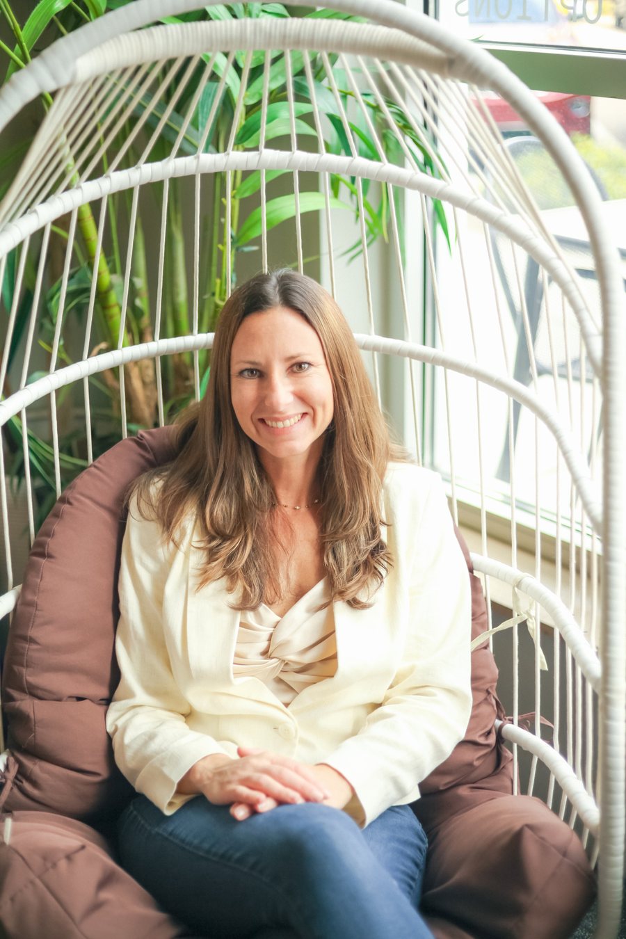 Julie Giancola smiling in a hanging chair at a Sarasota cafe
